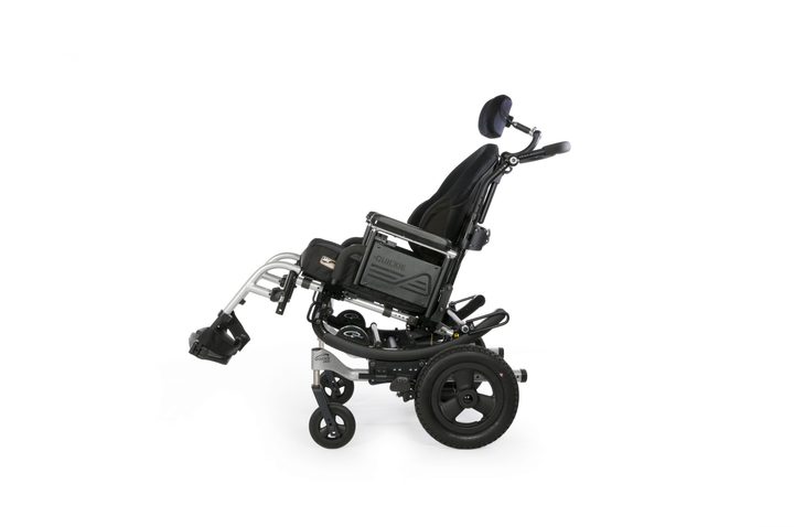 A complex-rehab power chair with a contoured back and headrest, seen at an angle.