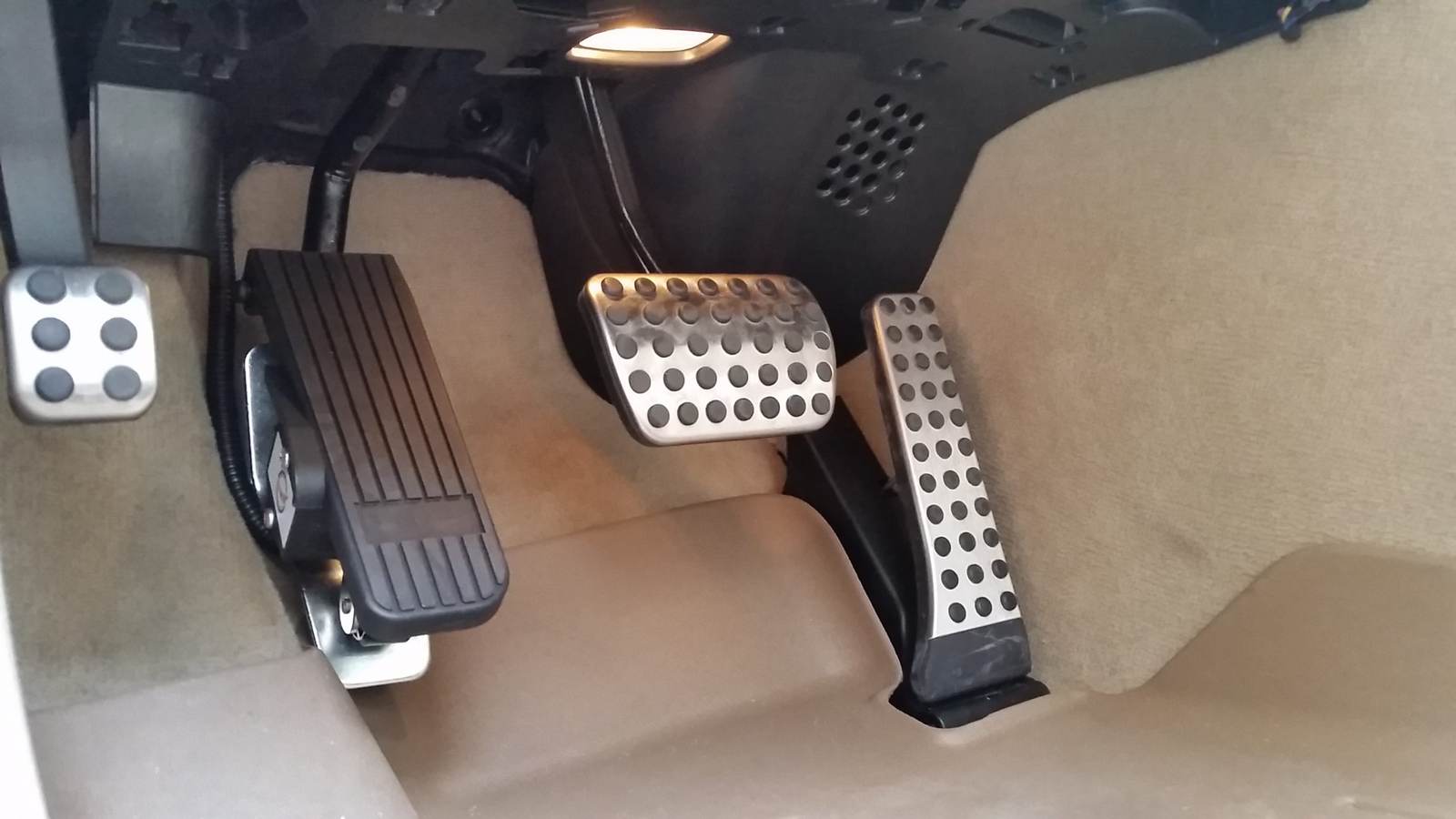 A left-foot accelerator pedal installed in a vehicle footwell alongside the original pedals.