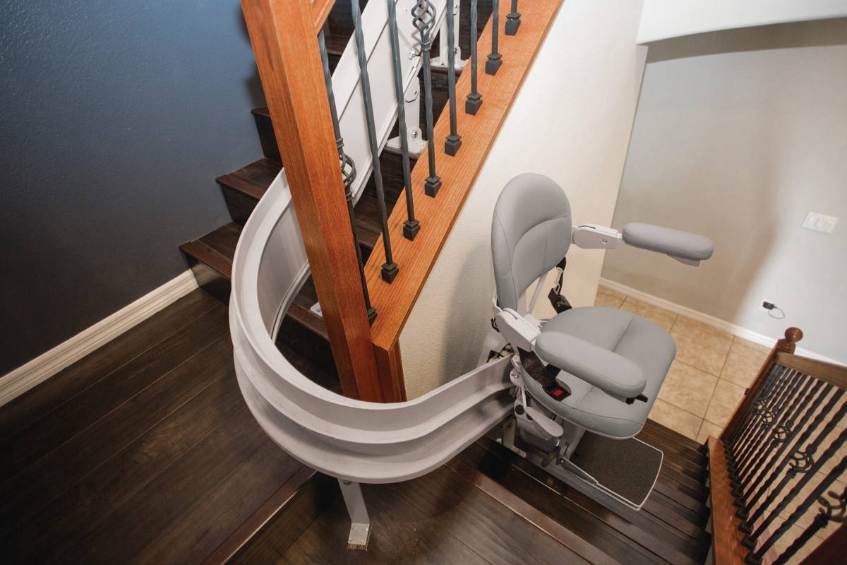 A stairlift on a curved rail following a turning staircase in a home.