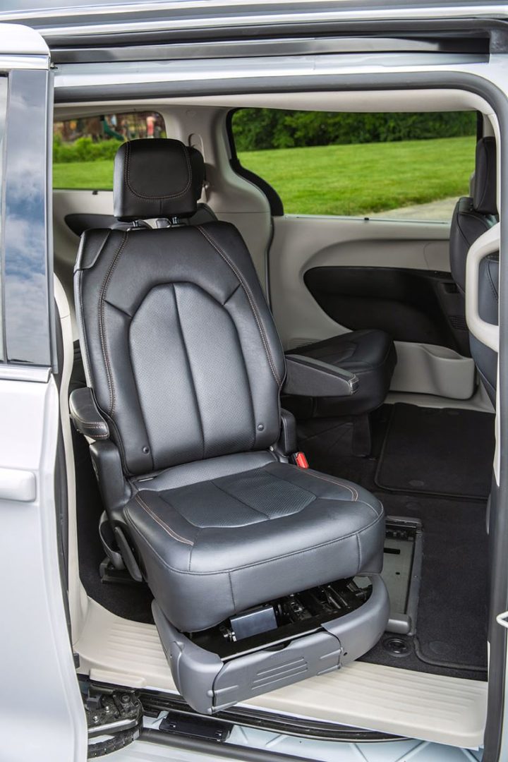 A powered transfer seat turned out through a van's side door, ready to be lowered to the ground.