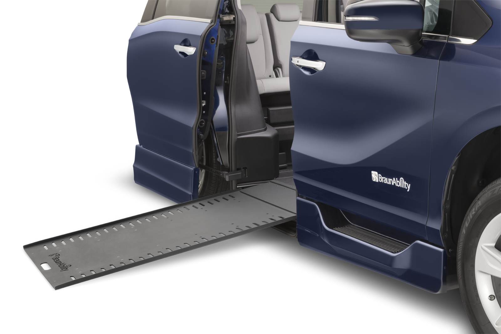 A converted minivan with its side door open and an in-floor ramp extended to the curb.